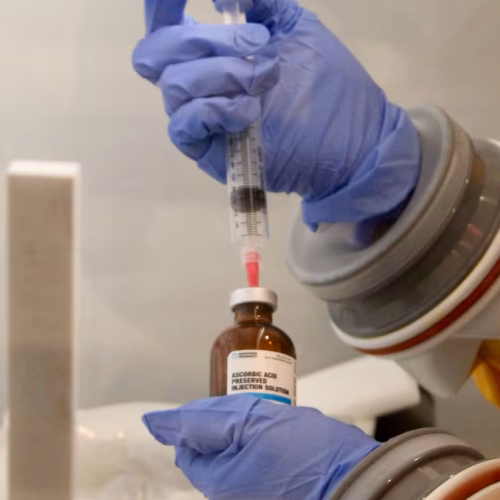 Licensed nurse preparing an IV infusion in a sterile clinical setting